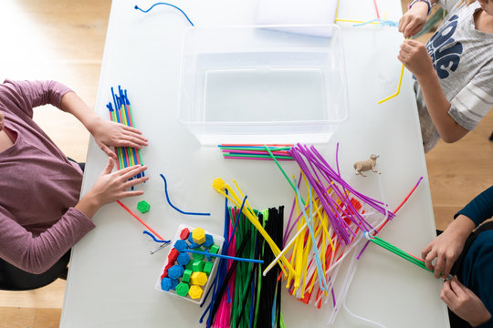 Directly above view of children building boats with pipe cleaners and staws as part of STEM project