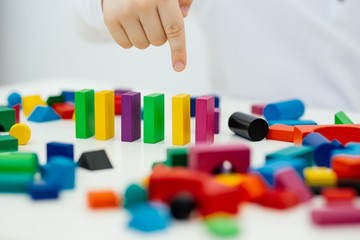 Building items in a single row. Concept of diagnostics of children's autism. A child plays with a colored wooden construction tool.