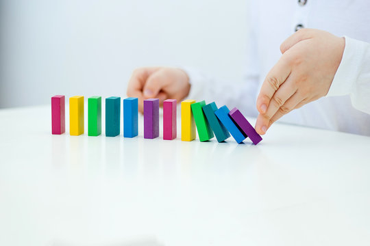 Building items in a single row. Concept of diagnostics of children's autism. A child plays with a colored wooden construction tool. Close.