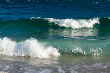 During windy days, the water of Lake Garda reaches the shore forming frothy and shiny waves that break and stretch on the pebble beach. In autumn the water has a very dark blue color. Italy.