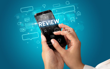 Female hand typing on smartphone with REVIEW inscription, social media concept