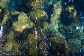 Naklejka na ściany i meble Just below the surface of the lake you can see stones and rocks of different sizes. The crystal water enhances the colors of the dolomite and the granite, with green, brown, gray and blue shades.