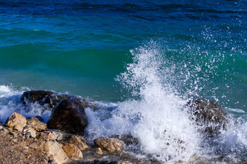 Splashes of water on the shore of Lake Garda. The waves break on the shore on a windy November day. In autumn the deep waters of the lake have a very dark and intense blue color. Lombardy Italy.
