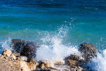 Splashes of water on the shore of Lake Garda. The waves break on the shore on a windy November day. In autumn the deep waters of the lake have a very dark and intense blue color. Lombardy Italy.
