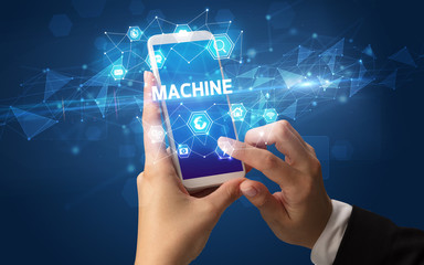 Female hand holding smartphone with MACHINE inscription, modern technology concept