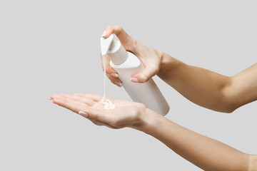 Female hands using hand sanitizer gel or liquid soap dispenser over light grey background