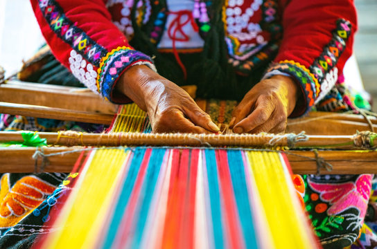 Peruvian indigenous Quechua woman weaving a textile with the traditional techniques in Cusco, Peru.
