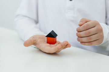 Concept of autism diagnosis and child development. A child holds a house made of colored wooden cubes in his hands. The control of behavior.