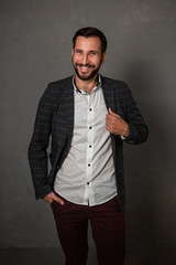 Fototapeta premium a smiling man is standing on a gray background in a jacket, white shirt and trousers