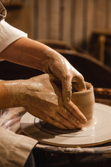 girl in an apron sculpts from clay on a potter's wheel