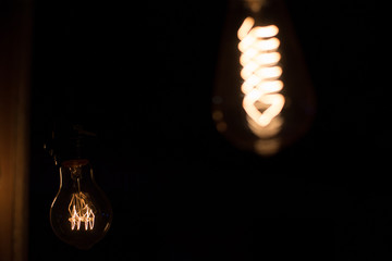 Edison lamp with warm light sways lightly on a black background