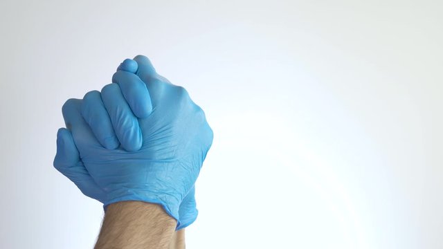 Medical hands with blue gloves clasping hands in a sign of strength and appreciation on white background. Symbolizing the fight and victory over diseases such as COVID-19 by coronavirus