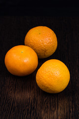 three mandarins on a dark brown background