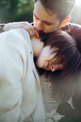 Loving hipster couple walking in the field, kissing and holding hands, hugging, lying in the grass in the spring at sunset. Photo with lens flare