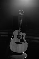 Fototapeta na wymiar A professional acoustic guitar stands on stage on a black background. Black and white photography
