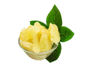 pieces of grapefruit lie in a glass vase on the background of a green branch