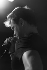 Young handsome guy emotionally sings and speaks into the microphone. Black and white photography