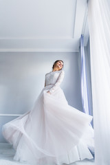 Fototapeta na wymiar bride in elegant wedding dress whirling by the window. have fun.