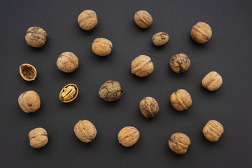 Top view of some walnuts with their shells and one is open. Black minimalism.