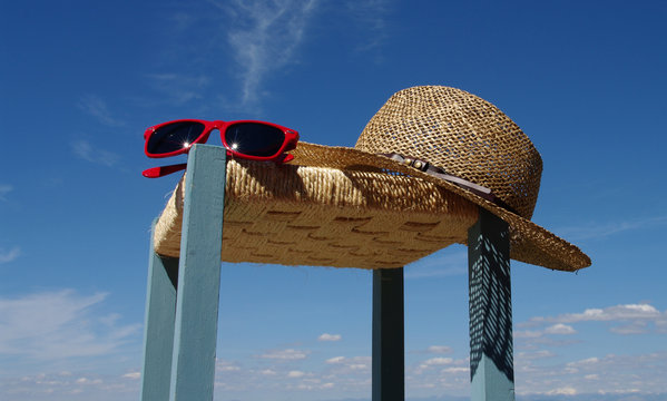 Sombrero y gafas de sol sobre taburete y cielo azul de verano