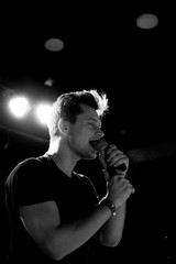 Young handsome guy emotionally sings and speaks into the microphone. Black and white photography