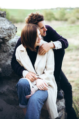 Young hipster couple in love with boyfriend and girl walking near rocks and forest. Have fun on vacation at sunset