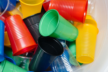 A large pile of multicolored plastic cups scattered on the floor. Pollution of the environment by...