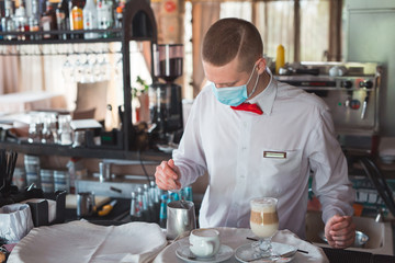 the waiter works in a restaurant in a medical mask.