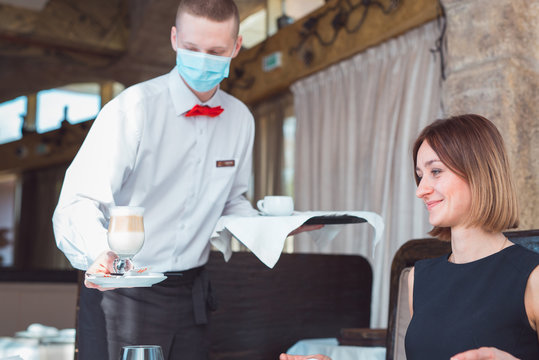 the waiter works in a restaurant in a medical mask.