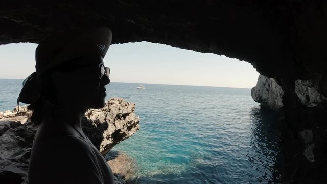 A young girl looking at the sea from inside a sea cave near Paphos, Cypris. A shot from the inside of a sea cave in the Meditteranean with a girl enjoying the calm sea waters.