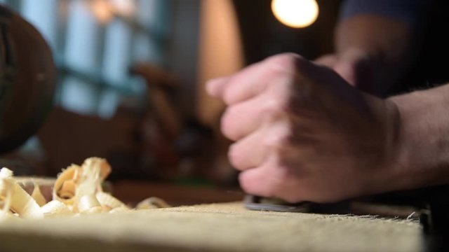 Carpenter with a planer at work in the workshop. Slow-motion close-up