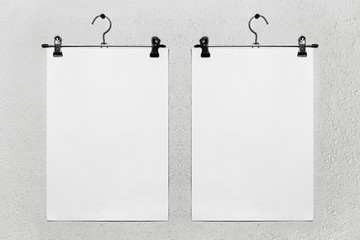 Close-up mockup of two white empty paper attached to hanger on white textured background.