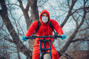 Young man in medical mask and gloves coughing in countryside. Adult male in red suit protecting yourself from diseases on walk. Concept of threat of coronavirus epidemic infection.