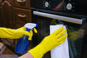 Hands in rubber gloves with a rag and detergent, wipe the oven in the kitchen. House cleaning.
