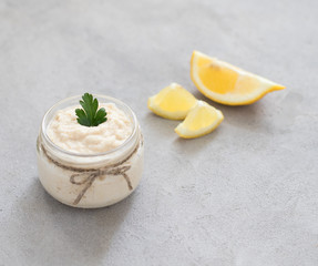 Appetizer white horseradish with lemon in a jar on a light background in rustic style