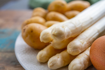 Ingredients for spring vegetarian dinner, high quality Dutch white asparagus, washed and peeled on board, ready to cookand, young potatoes, eggs and sauce