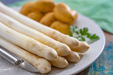 Ingredients for spring vegetarian dinner, high quality Dutch white asparagus, washed and peeled on board, ready to cookand and young potatoes