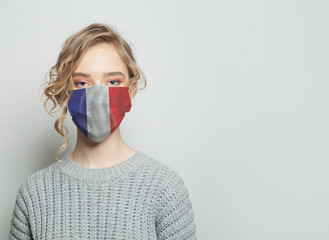 Young woman wearing a face mask with flag. Flu epidemic and virus protection concept