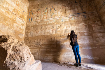 mujer joven tocando una pared de jeroglíficos en Egipto 