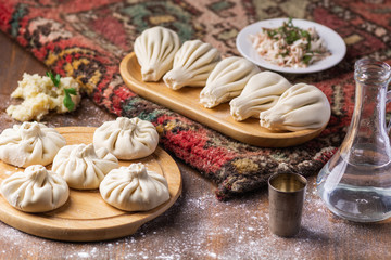 Obraz na płótnie Canvas Georgian dumplings Khinkali with potato and mushroom, Vegan food, Georgian Chacha (vodka) on a wooden background
