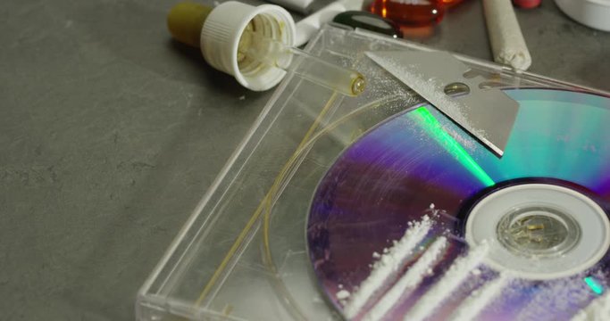 Lines of cocaine on CD next to hash oil and other illegal pills