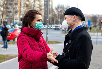 Young couple wearing masks for protection from viruses, smog, and other atmospheric pollutants in big city. Coronavirus contagion prevention measures during covid-19 pandemic. Selective focus.