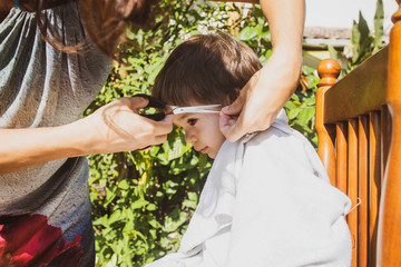 Mother cutting her toddler hair at home during the covid 19 quarantine. Coronavirus pandemic family self isolation.