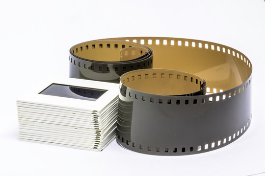 Rolled undeveloped film strip and film slide 35mm stack isolated on white background
