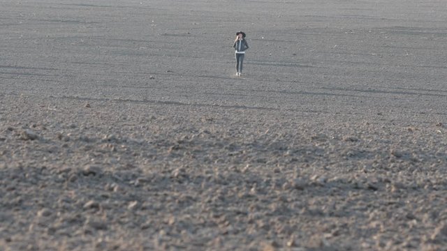 Cowgirl or cowboy girl walking on empty field at sunset wearing cawboy hat. 4K