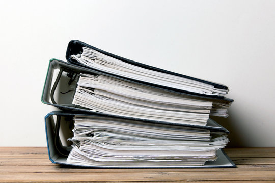 A stack of folders with documents on a wooden table
