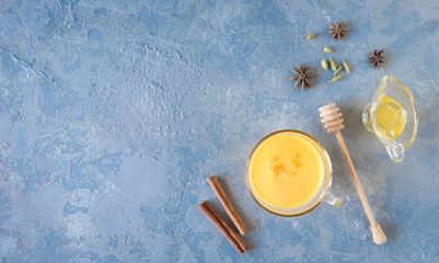 Obraz na płótnie Canvas Cup of golden turmeric latte milk with curcuma powder on gray. Top view.