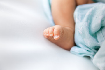Closeup of newborn foot and toes on a white background with copyspace on the left