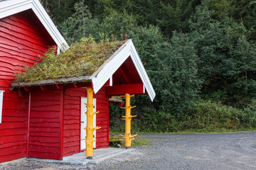 Fototapeta na wymiar Red wooden traditional scandinavian green grass roof hut house in Norway. North living culture cottage