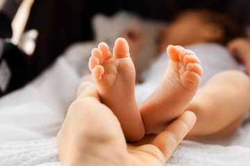 Little newborn feet in mother’s hand, infant barefoot, maternity and babyhood concept